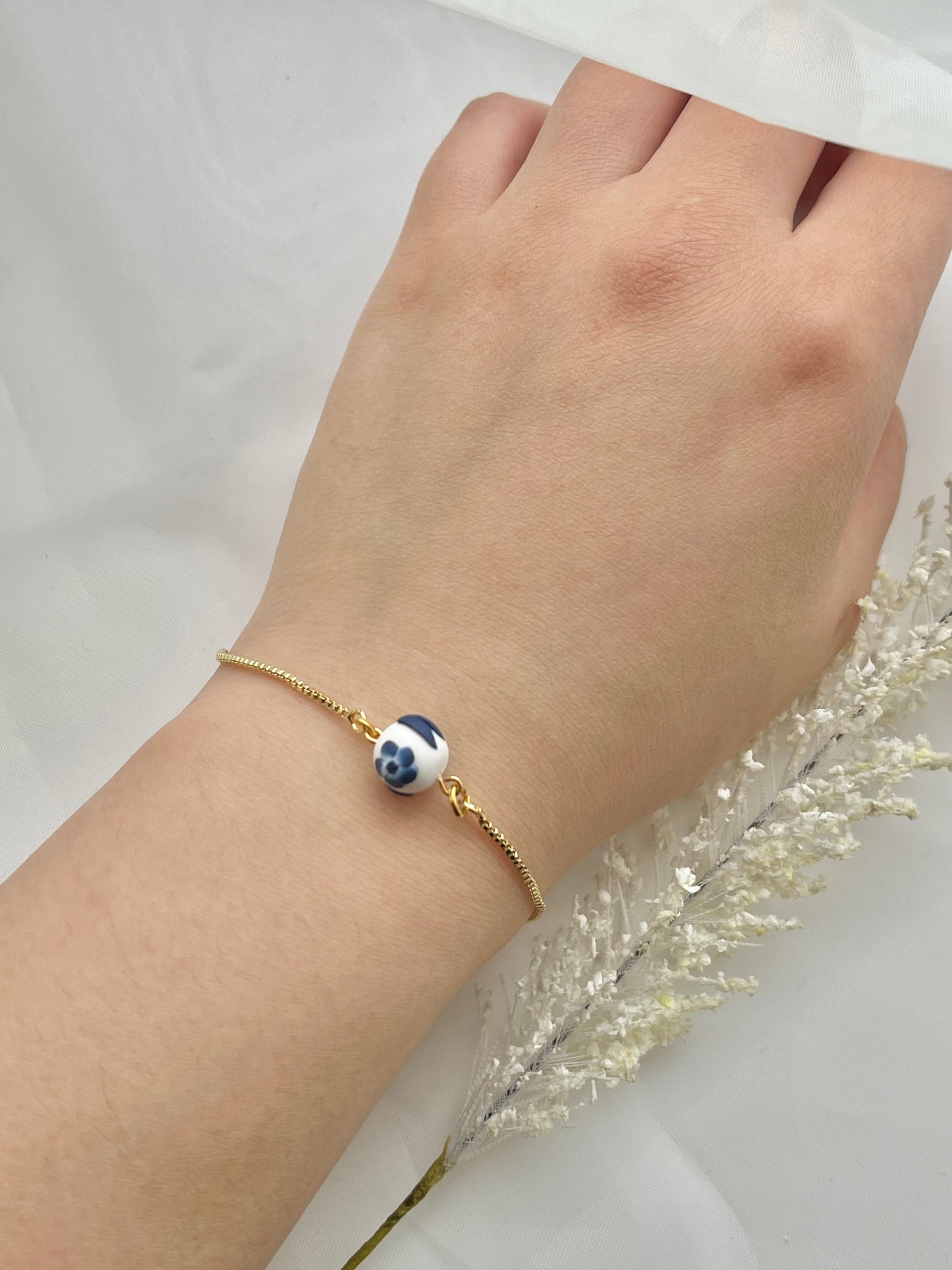 A floral bracelet in blue and white china pottery style with 1 bead on a hand