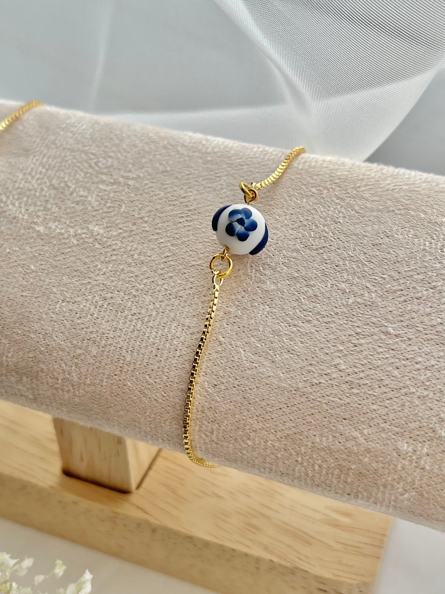 A floral bracelet in blue and white china pottery style with 1 bead on a bracelet holder