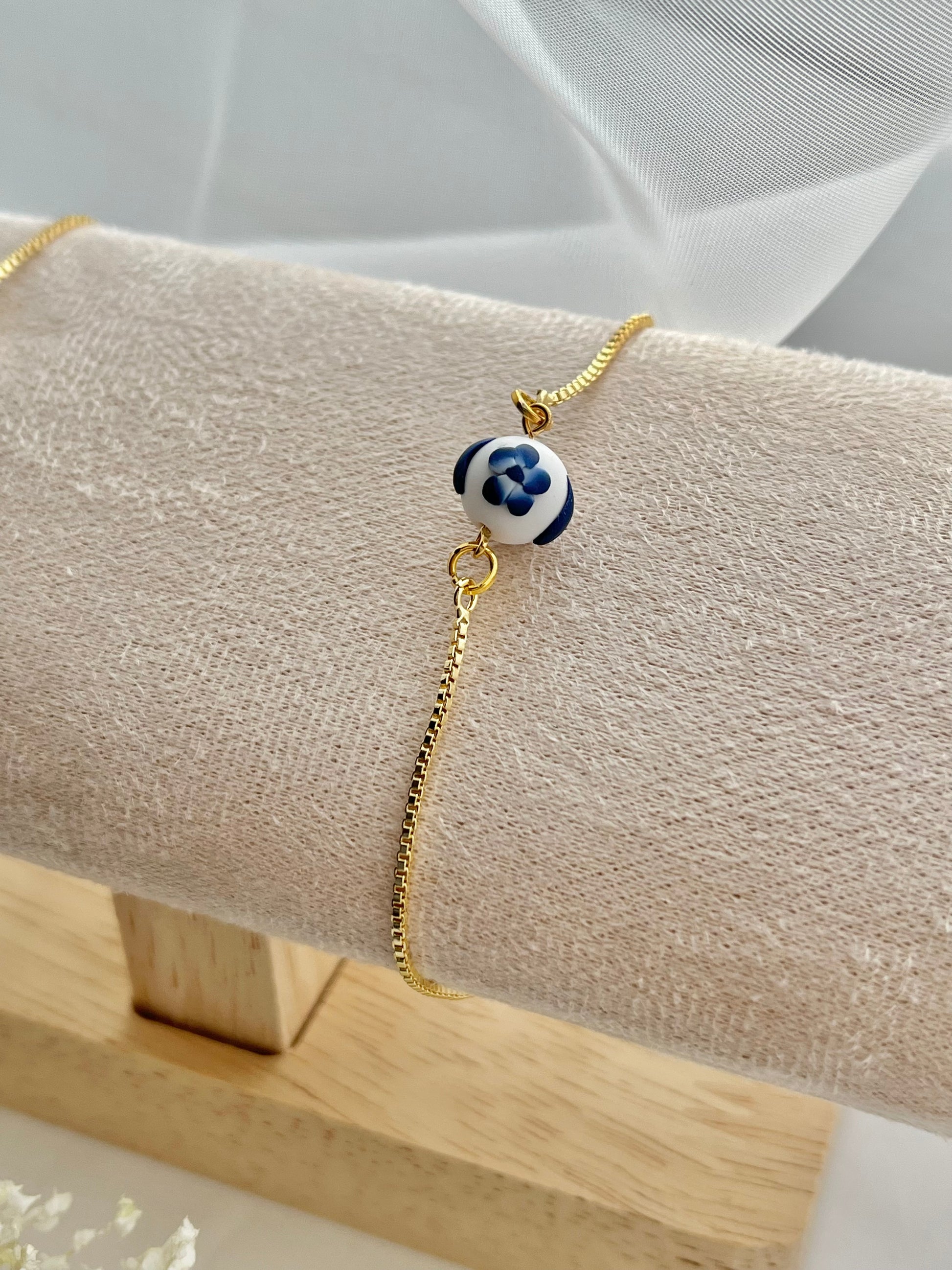 A floral bracelet in blue and white china pottery style with 1 bead on a bracelet holder