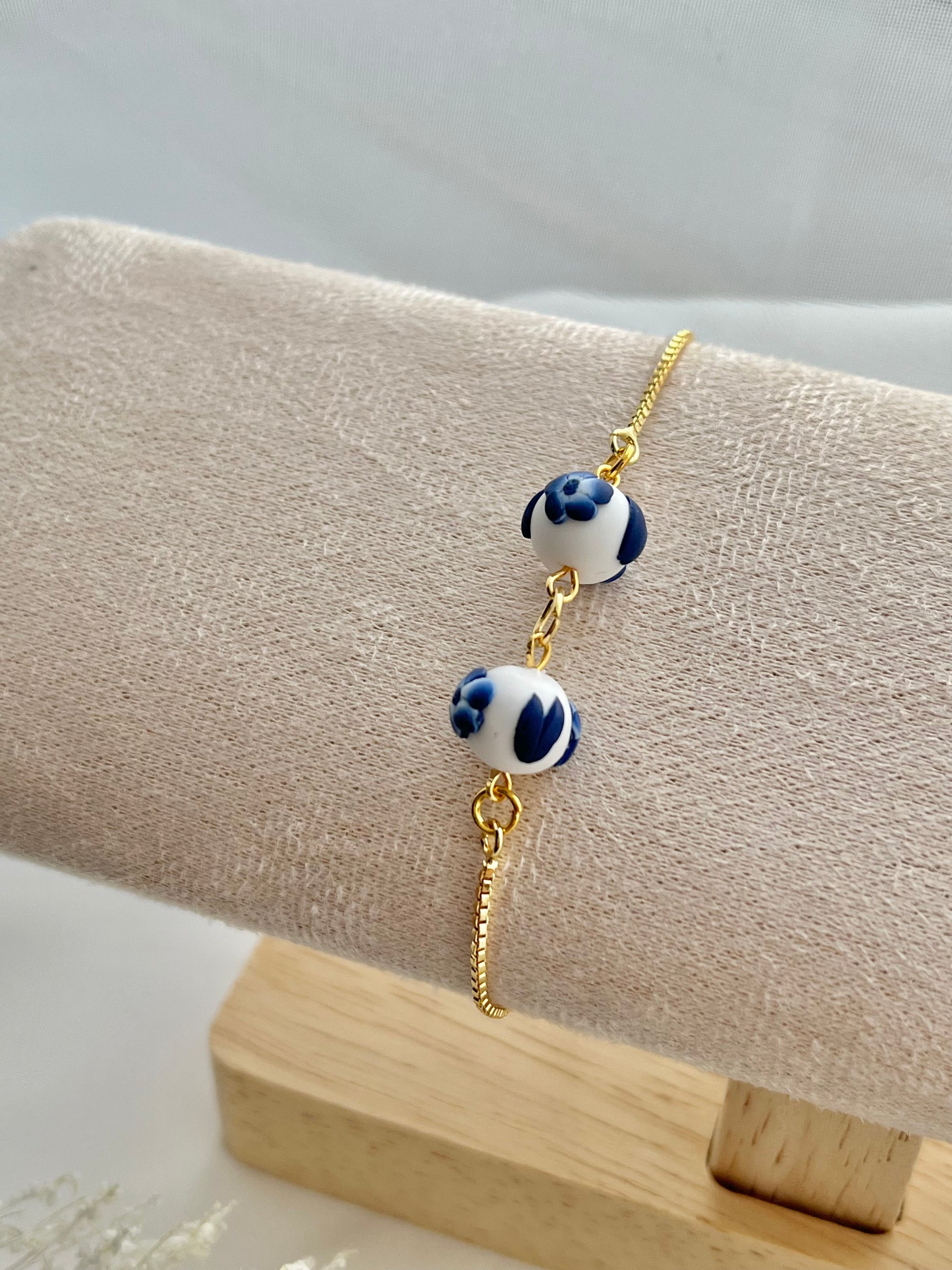 A floral bracelet in blue and white china pottery style with 2 beads on a bracelet holder