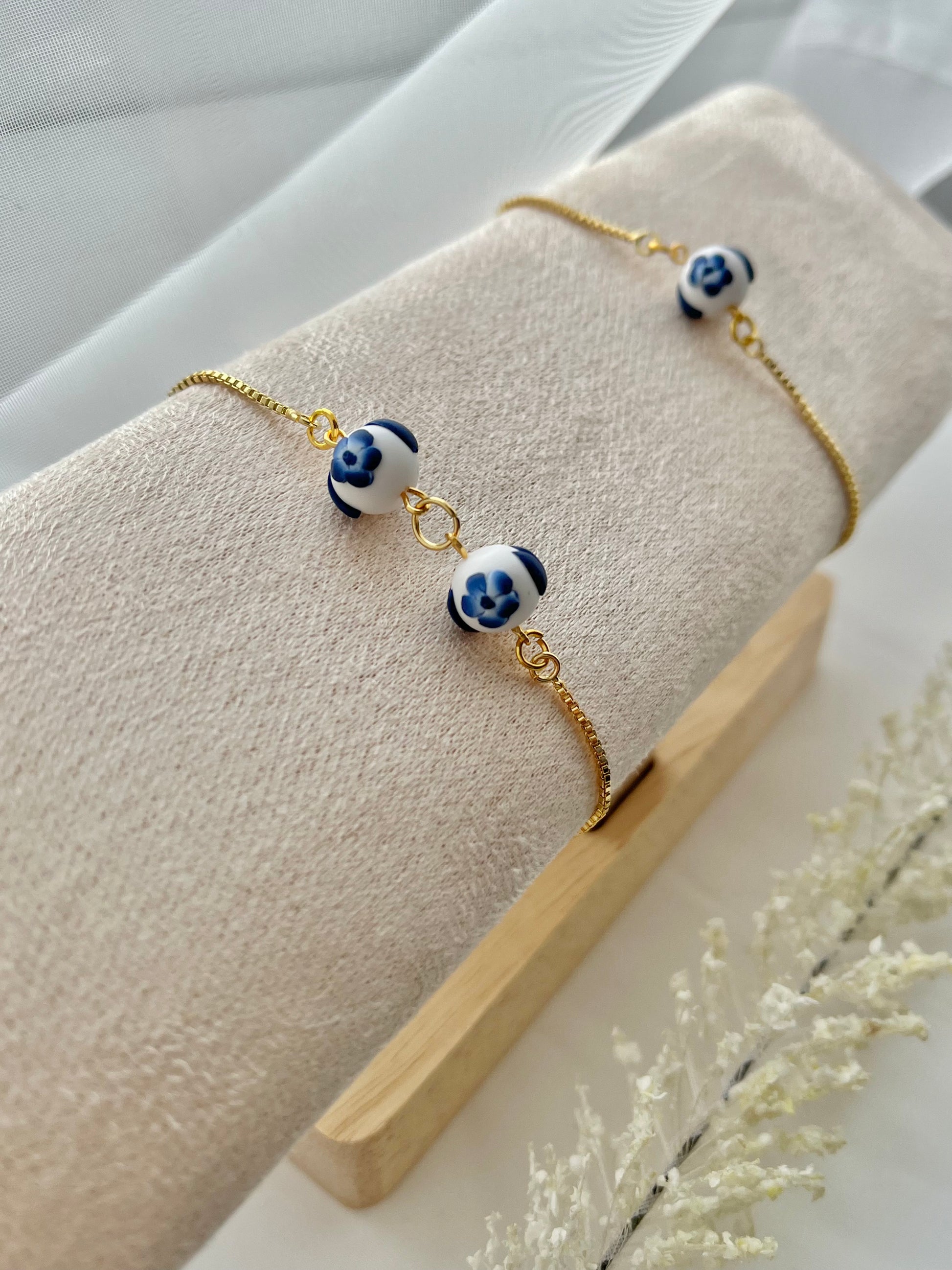 Two floral bracelets in blue and white china pottery style on a bracelet holder