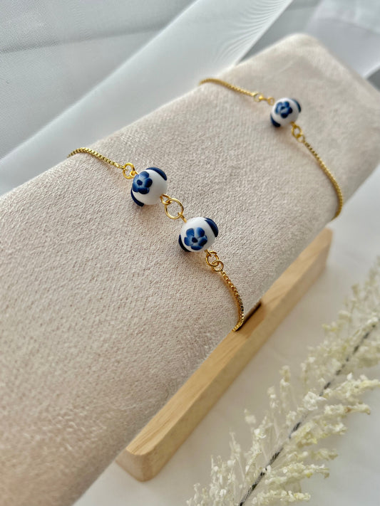 Two floral bracelets in blue and white china pottery style on a bracelet holder