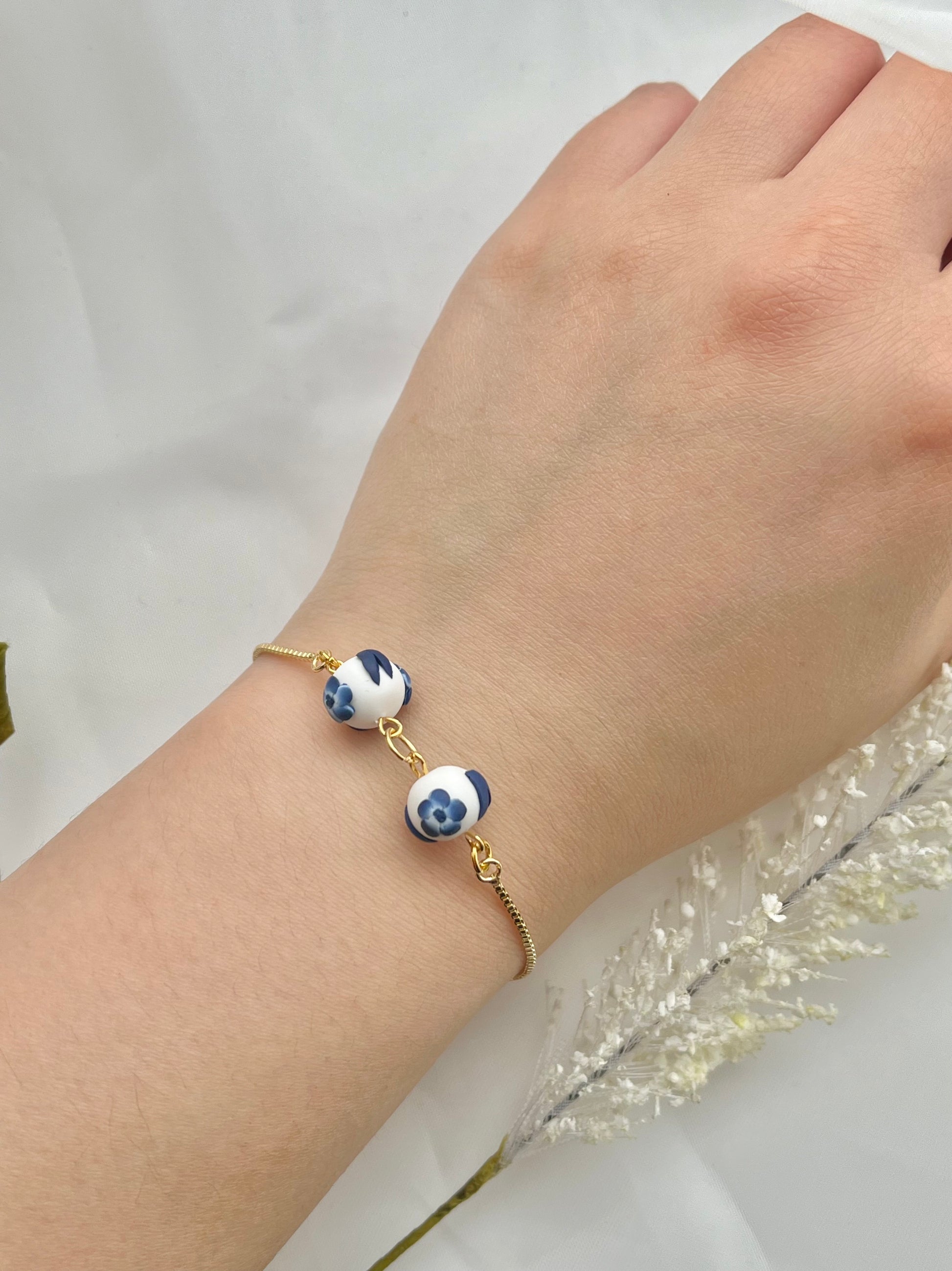 A floral bracelet in blue and white china pottery style with 2 beads on a hand