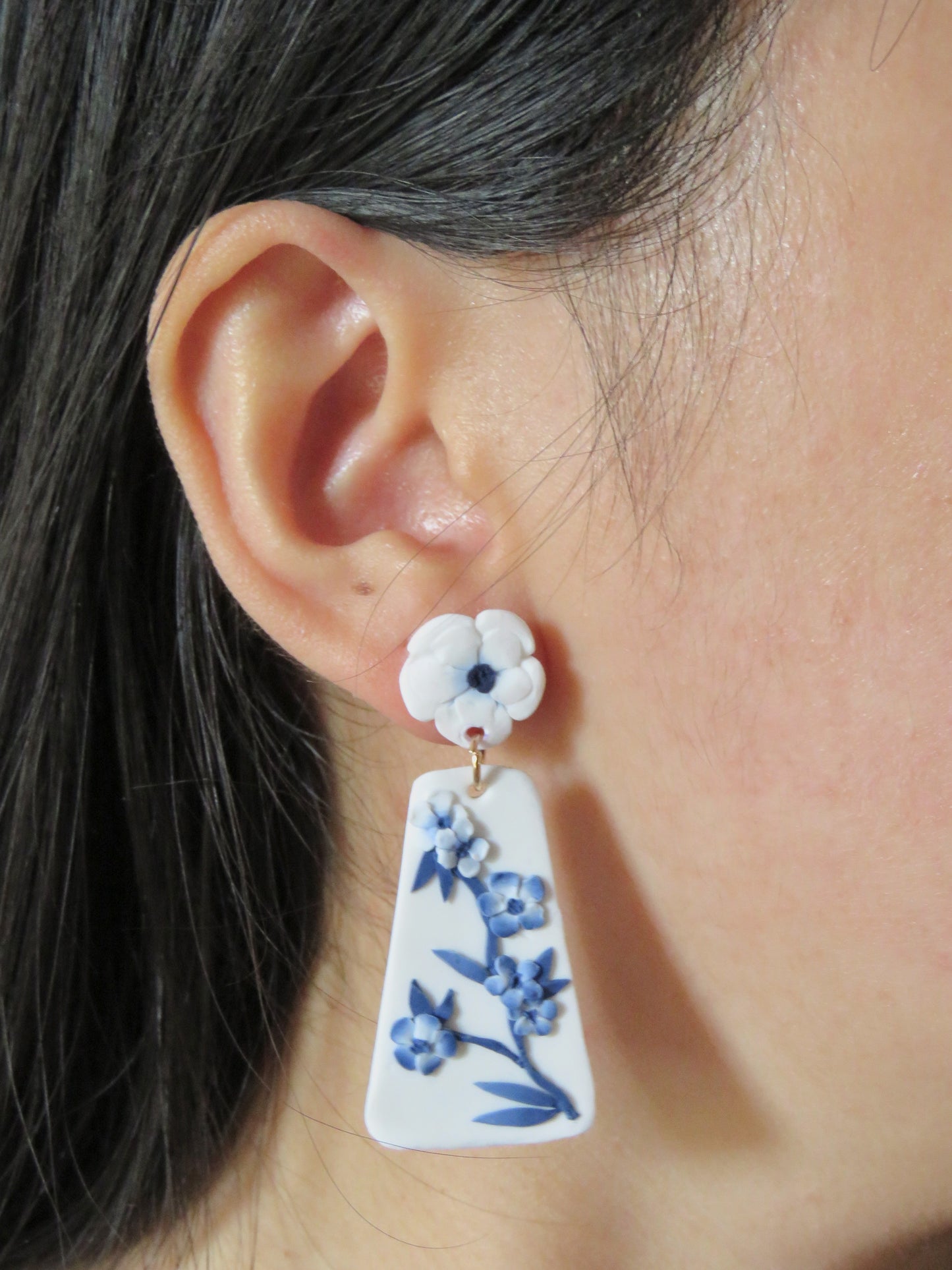 A girl wearing a long blue and white floral blue china clay earring