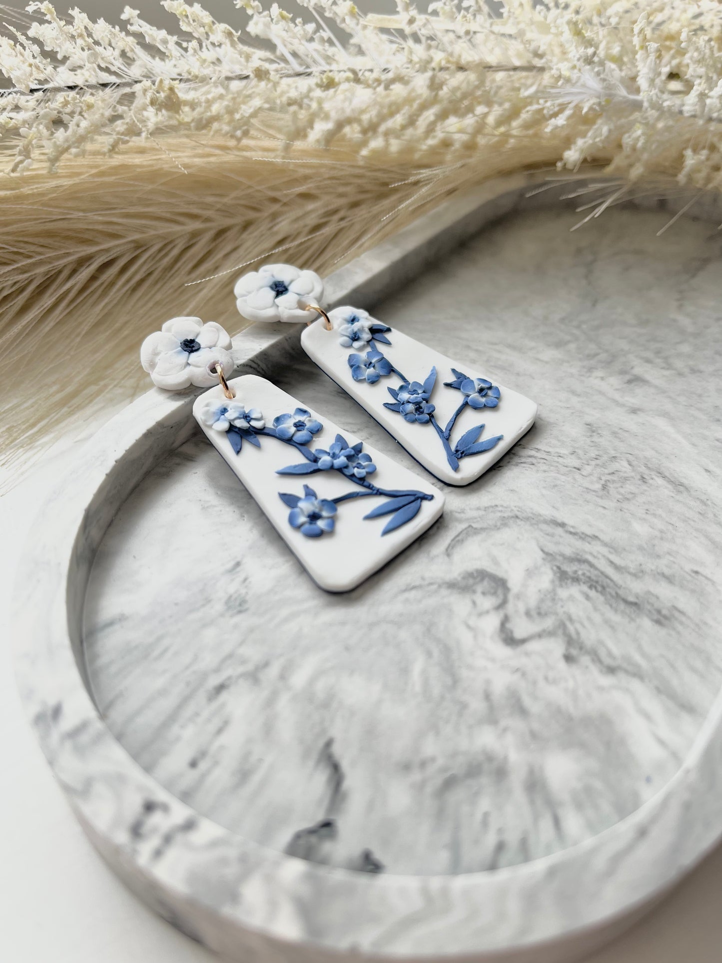 Long blue and white floral blue china clay earrings on a grey trinket dish