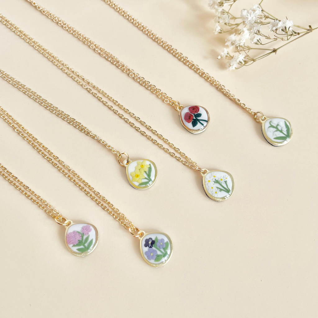 Smiling woman wearing an arch earrings with a blue and white floral pattern against a white background.