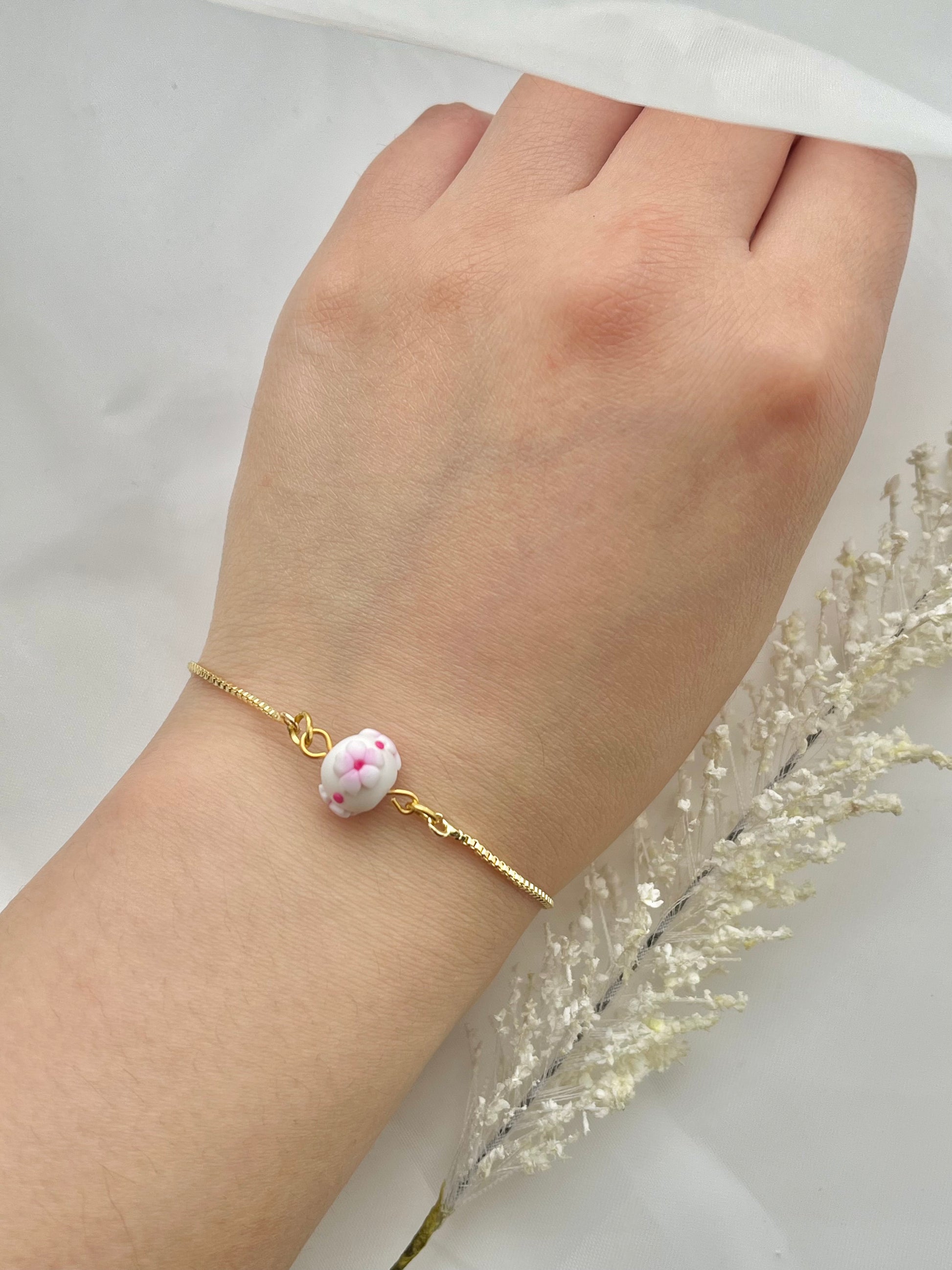 A floral bracelet in cherry blossom style with 1 bead on a hand