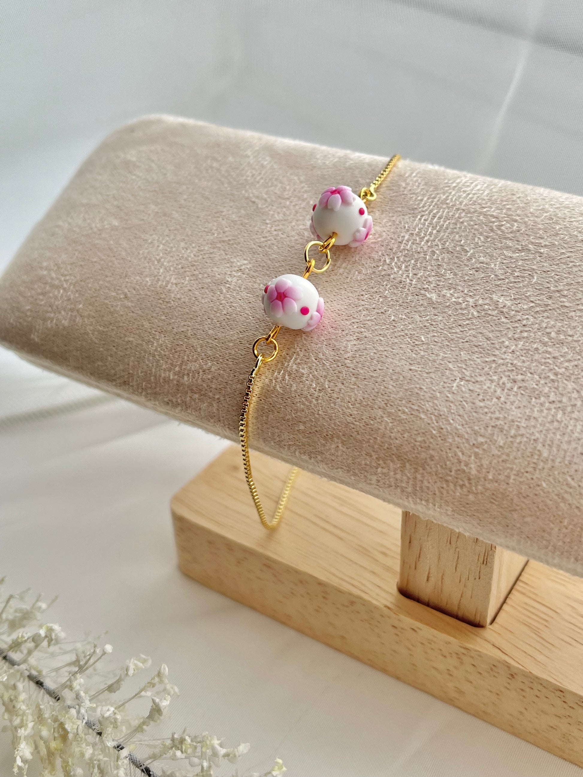 One floral bracelet in cherry blossom style with 2 beads on a bracelet stand