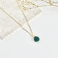 Gold clay necklace with a green pendant on a light background