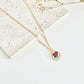 Gold clay necklace with a rose pendant on a light surface next to dried flowers