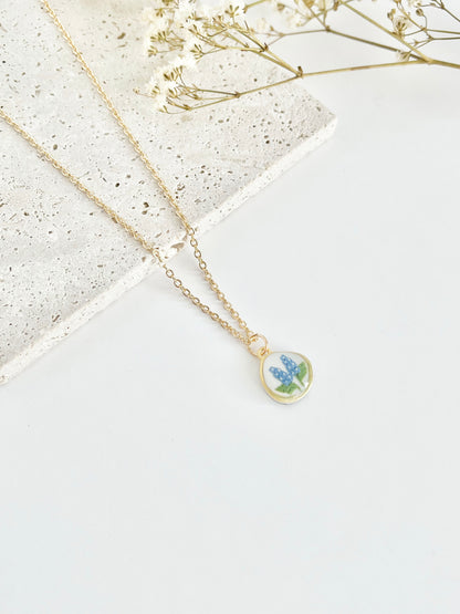 Gold clay necklace with a pendant featuring a floral design on a light background