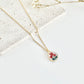 Gold clay necklace with a small pendant featuring poppies on a light surface next to dried flowers