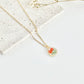 Gold clay necklace with a floral pendant on a light surface