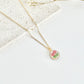 Gold clay necklace with a floral pendant on a light surface
