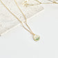 Gold clay necklace with a floral pendant on a light surface with dried flowers.