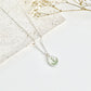 Silver clay necklace with a lily of the valley pendant on a white surface with dried flowers.