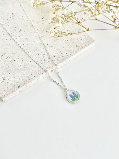 Silver clay necklace with a pendant featuring a floral design on a light background