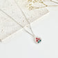 Silver clay necklace with a small pendant featuring poppies on a light surface next to dried flowers
