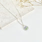 Silver clay necklace with a floral pendant on a light background next to dried flowers