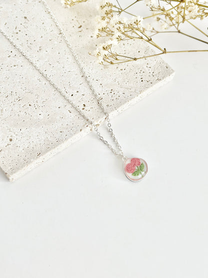 Silver clay necklace with a floral pendant on a light surface