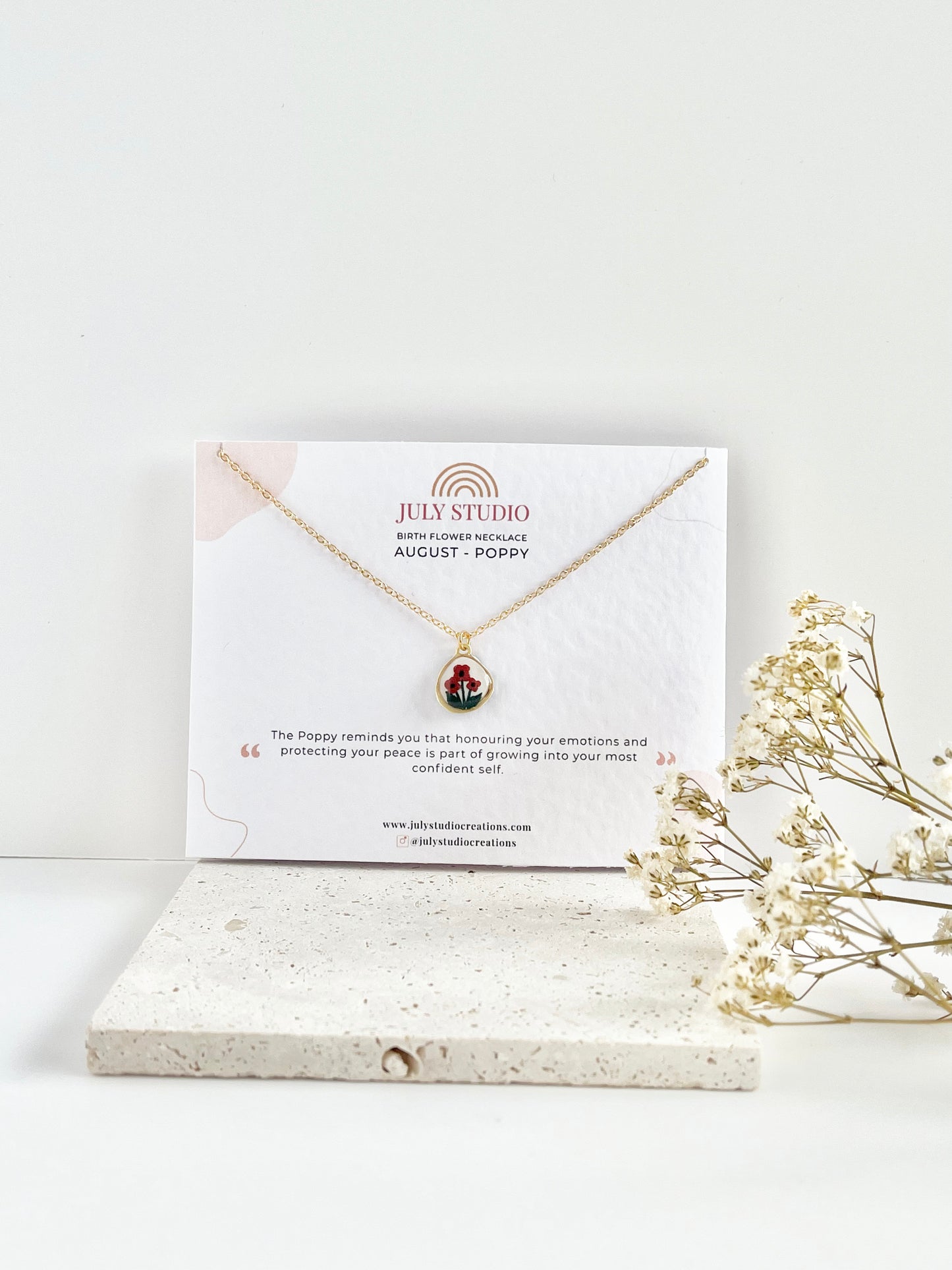 Gold clay necklace on a July Studio jewellery card card with a white background and dried flowers.