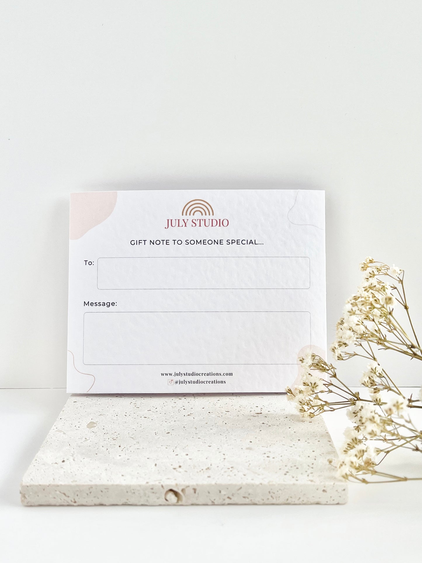Jewellery card with 'July Studio' branding with a gift note on a white surface with dried flowers.